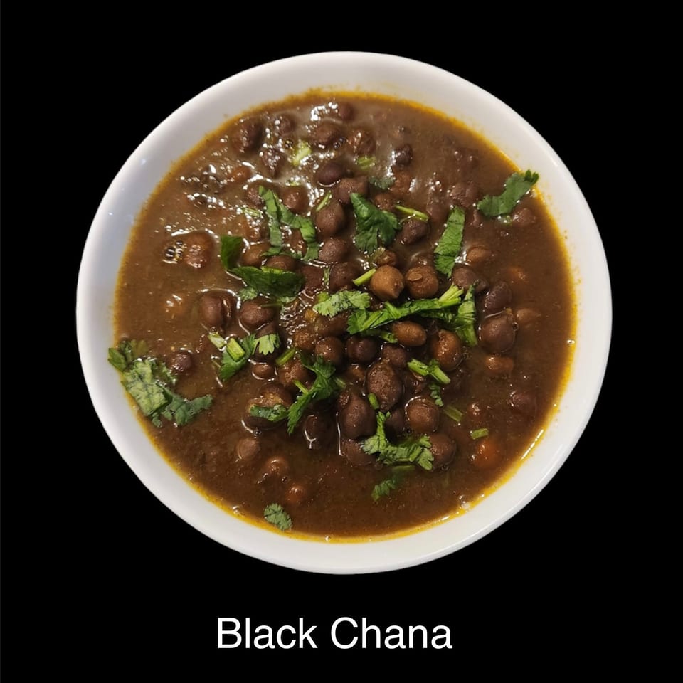 Bowl of black chana curry garnished with fresh cilantro.