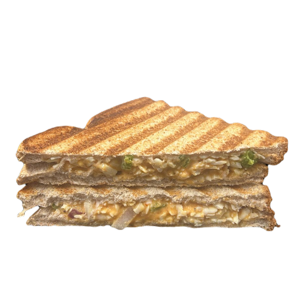 Grilled sandwich stacked with creamy shredded filling, onions, and herbs against a dark teal background.